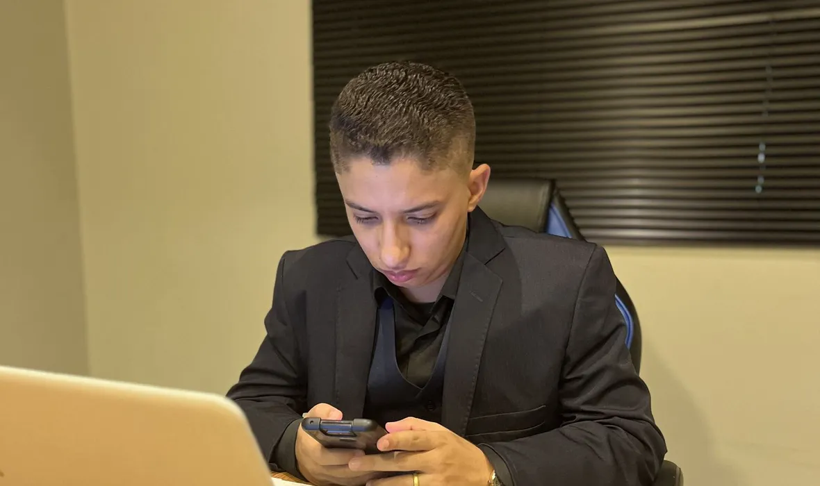 Consultor da EvoluaC respondendo mensagens de clientes no celular, sentado à mesa do escritório