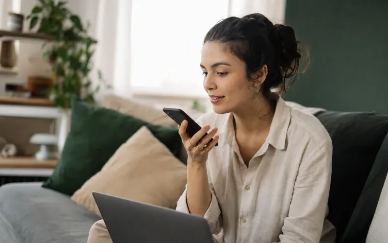 Jovem no sofá de casa pesquisando uma empresa da cidade num assistente de inteligência artificial pelo celular