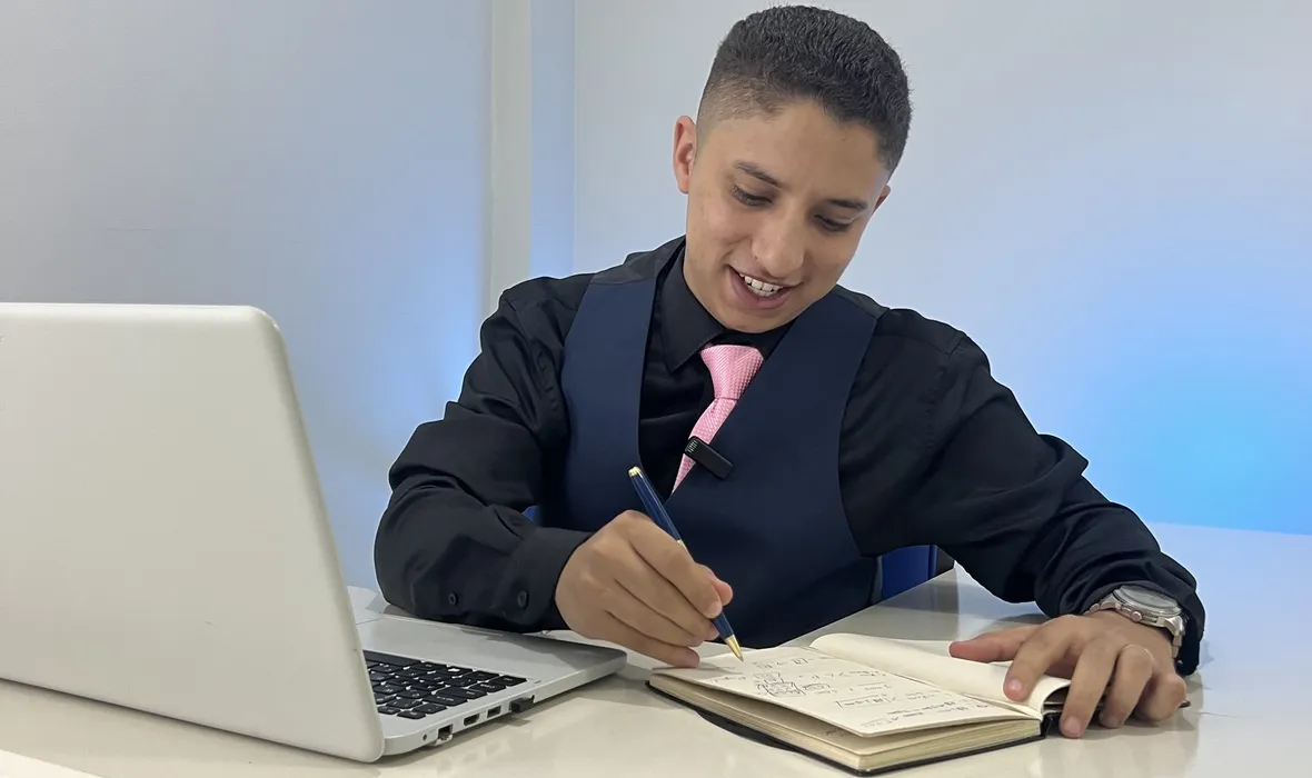 Consultor anotando o planejamento de marketing de um cliente, ao lado do notebook