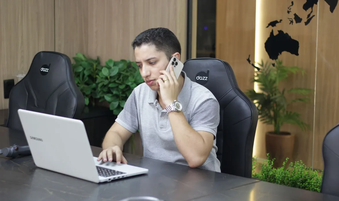 Consultor da EvoluaC ao telefone com um cliente, com o notebook aberto na mesa de reunião