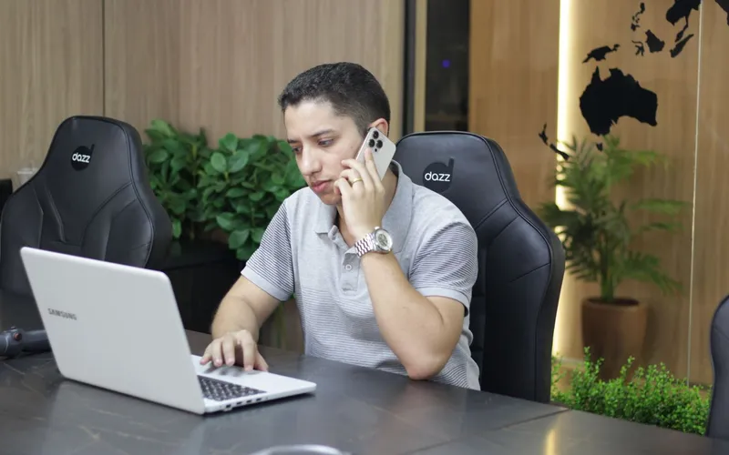 Consultor da EvoluaC ao telefone com um cliente, com o notebook aberto na mesa de reunião