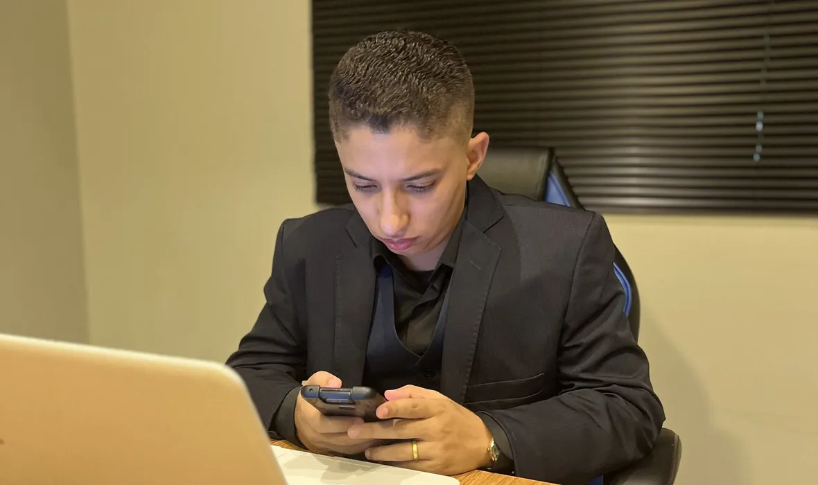 Consultor de marketing respondendo clientes pelo celular, com o notebook aberto